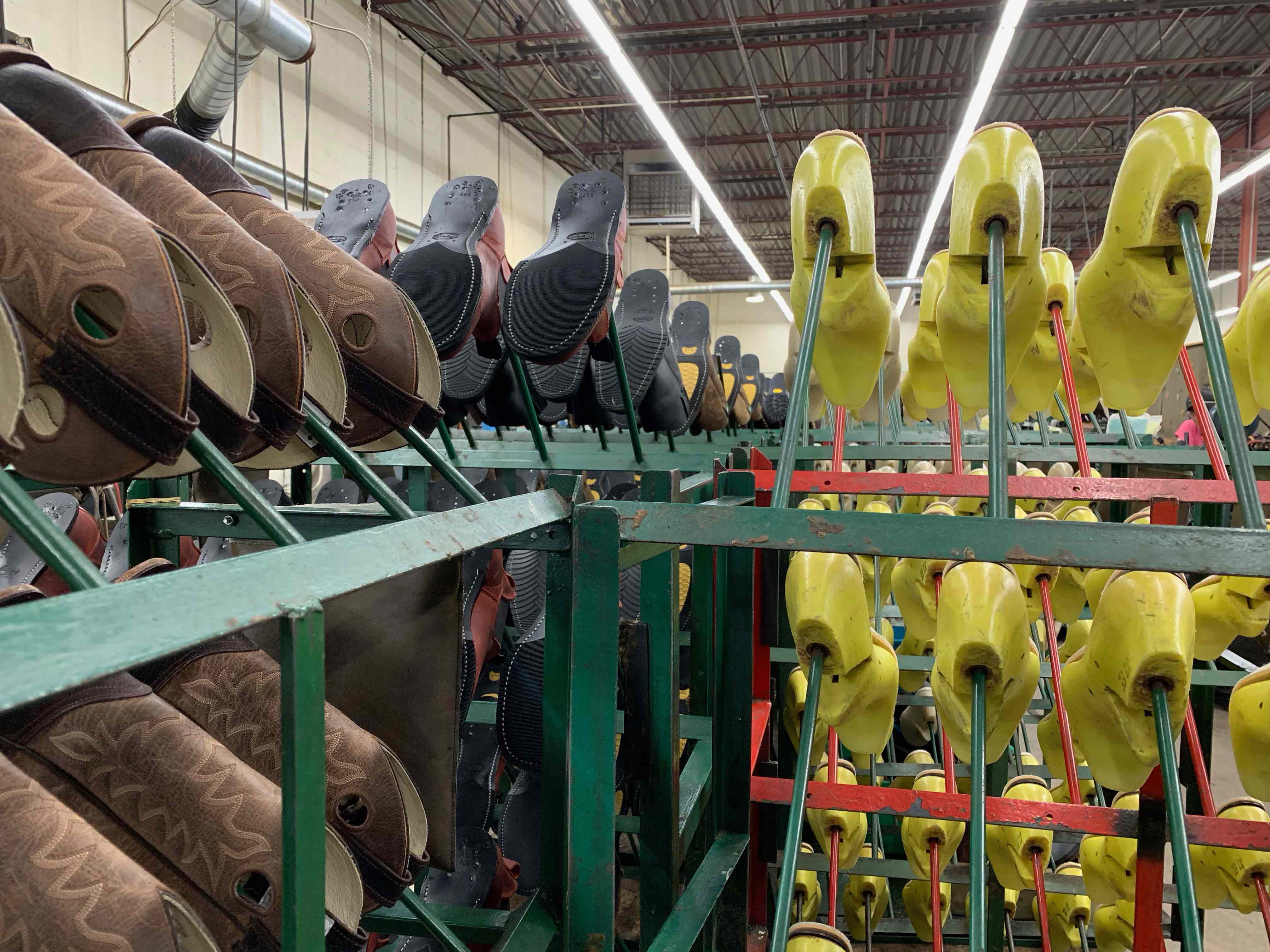 The various shoes and molds sit on racks, waiting for the next stage of the process.