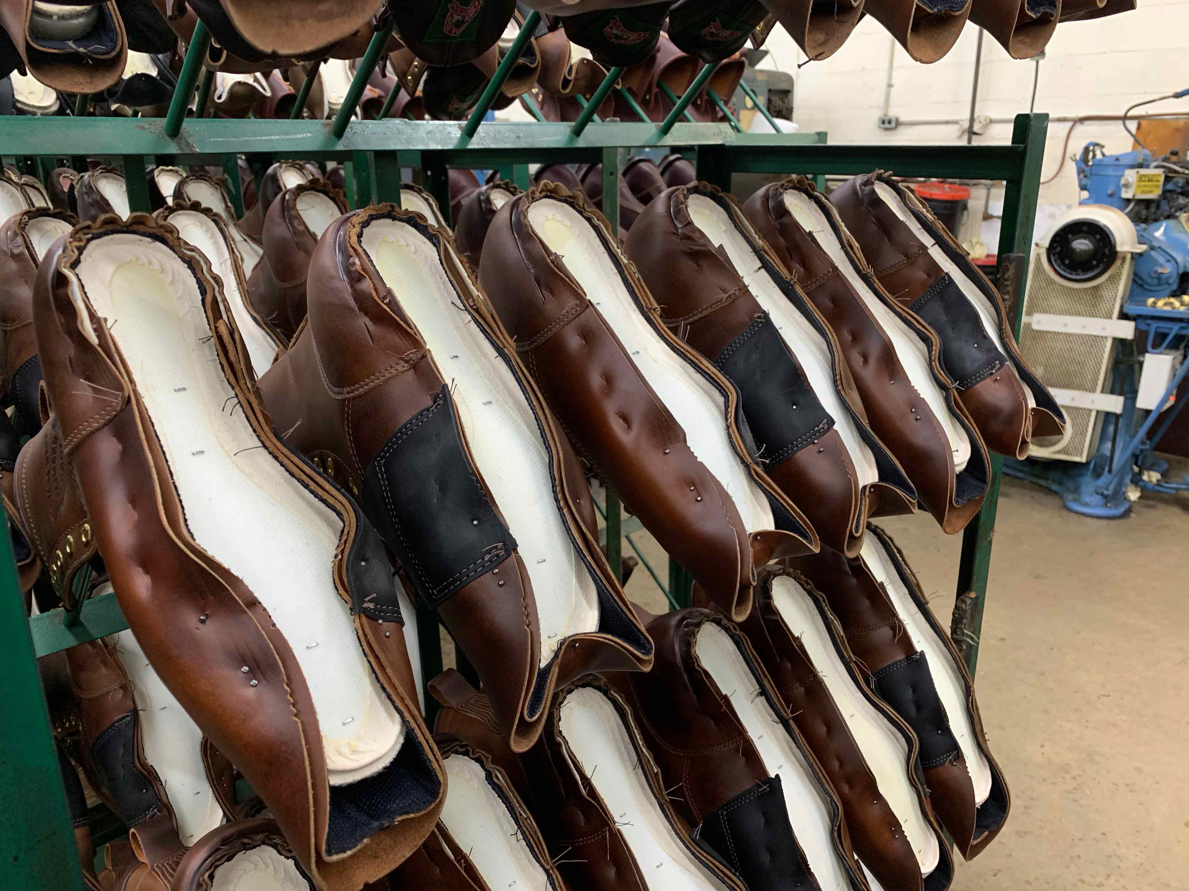 The shoes sit on racks, waiting for the next stage of the process.
