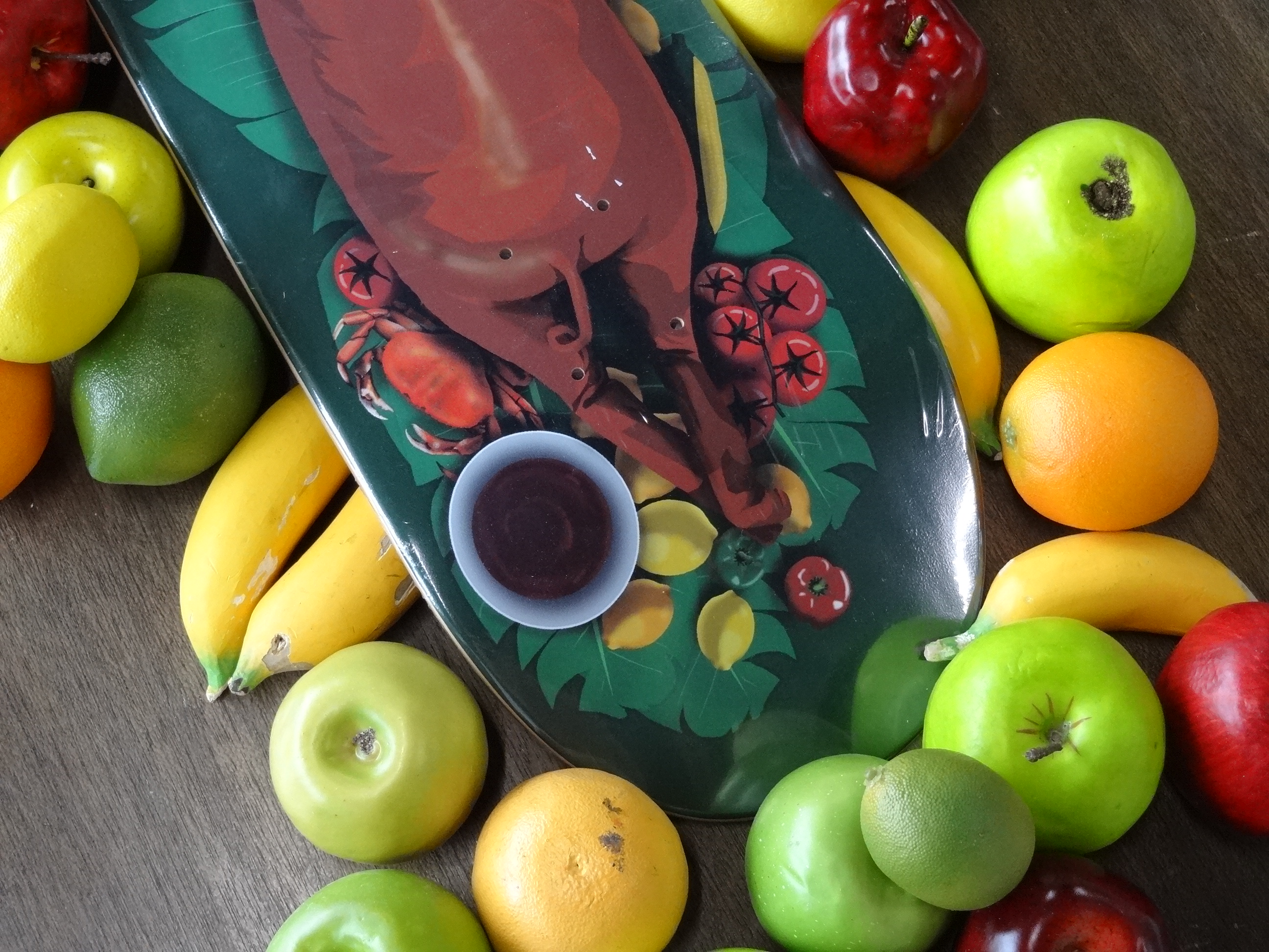 Lechon Skateboard amongst a pile of fruit